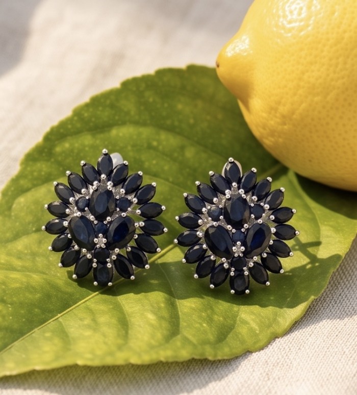 Giuseppina - Authentic 28.5 carat Sapphire rhodium over .925 Sterling Silver handcrafted Statement earrings - Close-up of Giuseppina sapphire earrings on a leaf with a lemon nearby.
