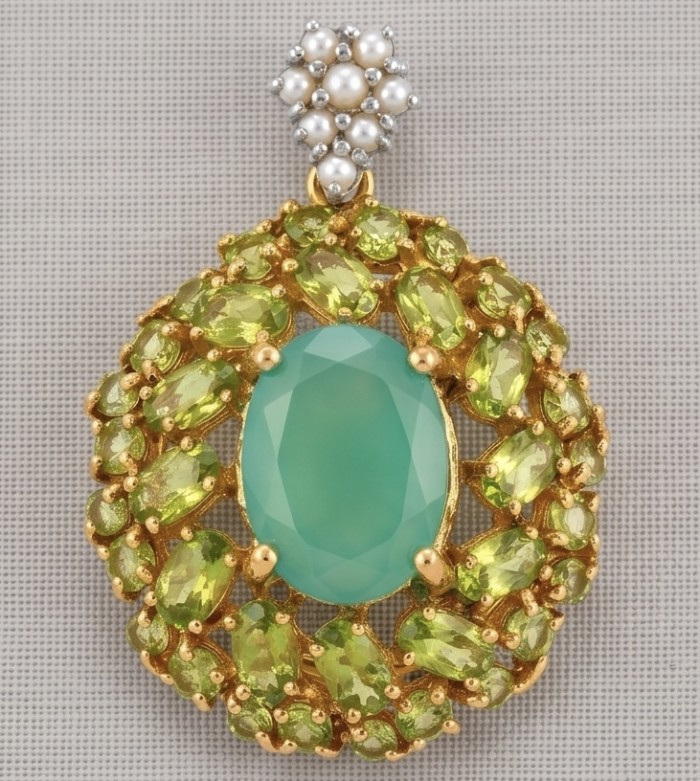 Green Royalty - 8.8 carat Colombian Emerald 6.4 carat Peridot .925 Sterling Silver dipped in 22K Gold handmade Statement pendant - Close-up of ornate pendant with emerald and peridot stones on fabric background.
