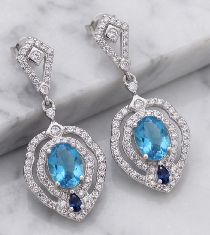 Tranquillity - 4.7 carat carved Swiss Blue Topaz .925 Sterling Silver dipped in Rhodium Handcrafted Statement earrings - Blue topaz earrings on marble surface, showcasing stone detail.
