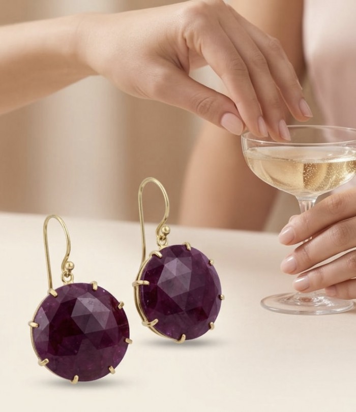 Giovanna Natural 22.2 carat Kasmir Ruby 18K Gold over .925 Sterling Silver handcrafted Statement earrings - Close-up of Giovanna Ruby Earrings with a hand holding a glass of champagne.